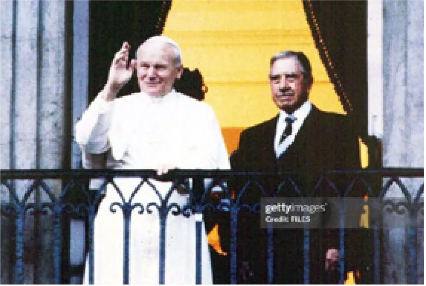 Photograph of Pope John Paul II, dressed in white, waving from a balcony draped in yellow, with General Augusto Pinochet in a dark suit standing just behind him. The image carries a Getty Images watermark.
